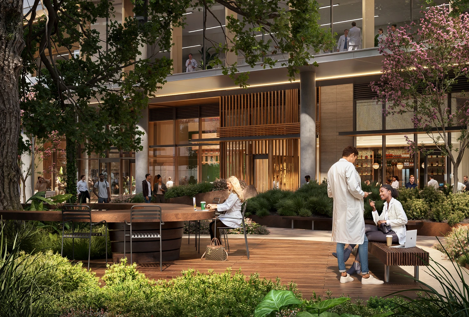 Researchers in lab coats converse outside office building courtyard with trees, seating, and natural greenery