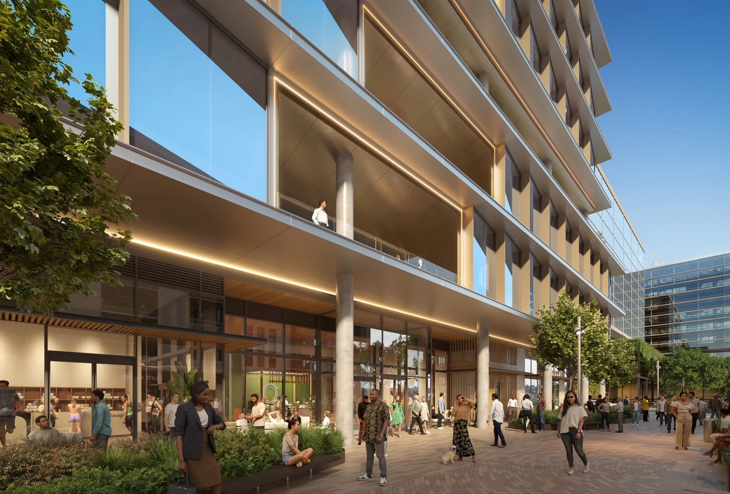 Street-level view of modern office building entrance with landscaped seating and active pedestrian traffic